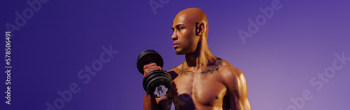 Muscular man doing exercise with weight dumbbells on studio background. Strength and motivation