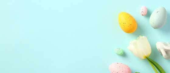 Happy Easter banner with space for text. Colorful Easter eggs, white tulip, Easter bunny on pastel blue background.