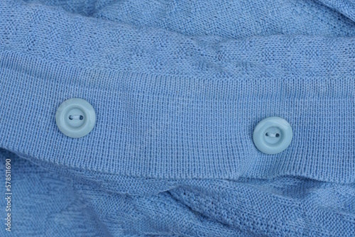 two round plastic buttons on a blue woolen garment fabric