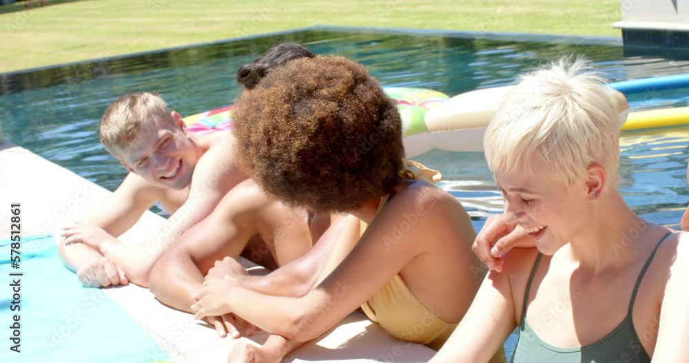 Happy diverse friends talking in water at pool party in summer Happy diverse friends talking in water at pool party in summer