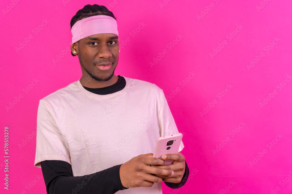 Black ethnic man with a phone in pink clothes on a pink background, talking on the phone Black ethnic man with a phone in pink clothes on a pink background, talking on the phone
