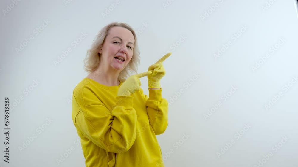 woman in yellow latex gloves and bright clothes points to an empty space for advertising the text of a cleaning cleaning company sincere smile narrowed green eyes Come call White studio woman in yellow latex gloves and bright clothes points to an empty space for advertising the text of a cleaning cleaning company sincere smile narrowed green eyes Come call White studio