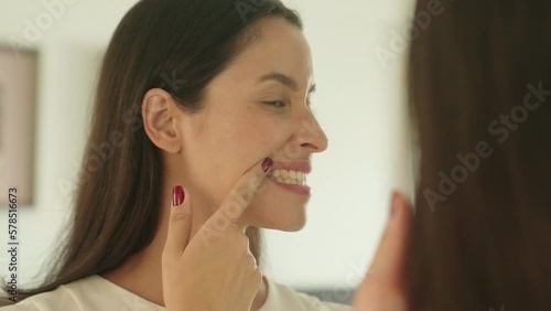 Wallpaper Mural Woman checking her teeth in mirror with opened mouth looking for caries in bathroom at home. Teeth health care concept.
 Torontodigital.ca