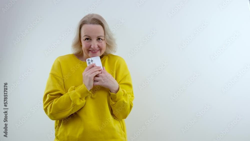 cute woman plotting something holding phone in her hands wants to call someone smiling secret surprise white background bright clothes middle age gift pleasant emotions joy surprise cute woman plotting something holding phone in her hands wants to call someone smiling secret surprise white background bright clothes middle age gift pleasant emotions joy surprise