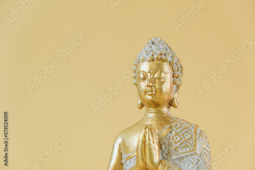 Buddha golden statue on beige background.Beautiful meditation and harmony background in golden colors. Meditation and relaxation symbol.Buddhism religion background.Calm, balance and harmony.