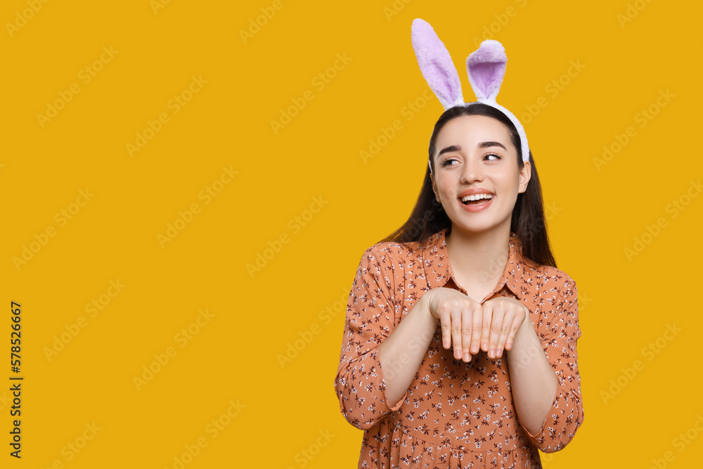 Happy woman wearing bunny ears headband on orange background, space for text. Easter celebration Happy woman wearing bunny ears headband on orange background, space for text. Easter celebration