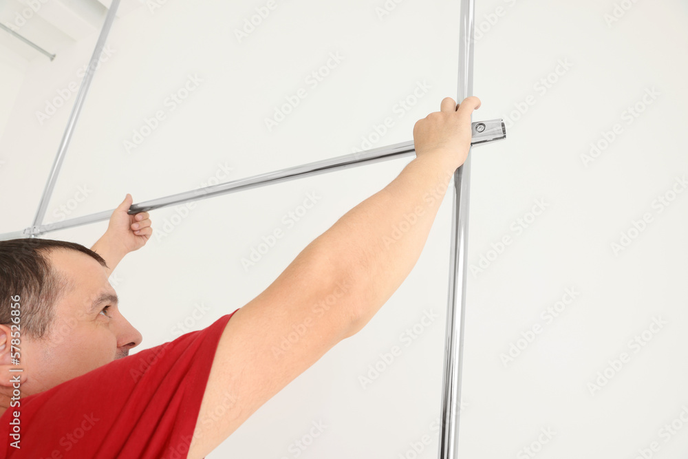 Worker installing new metal pipes indoors near white wall Worker installing new metal pipes indoors near white wall