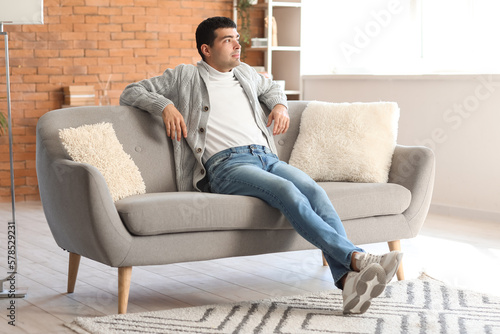 Young man resting on grey sofa at home © Pixel-Shot
