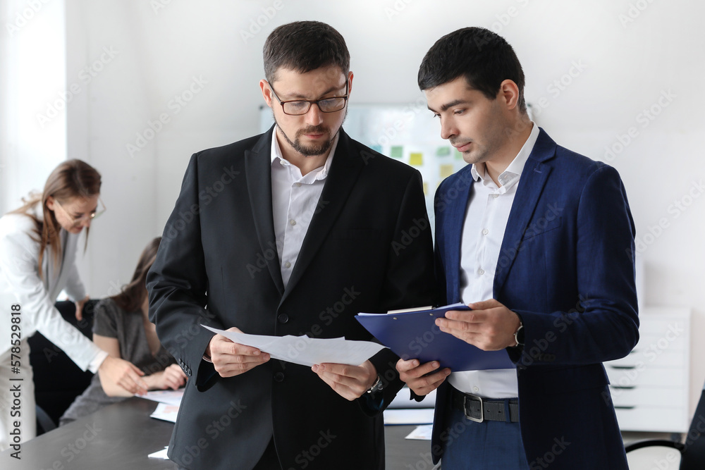 Male colleagues working on business plan in office Male colleagues working on business plan in office
