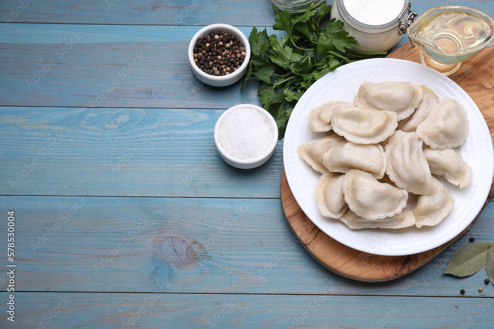 Delicious dumplings (varenyky) with potatoes served on light blue wooden table, flat lay. Space for text Delicious dumplings (varenyky) with potatoes served on light blue wooden table, flat lay. Space for text