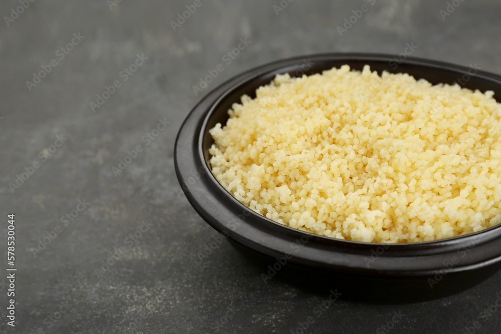 Bowl of tasty couscous on grey table, closeup. Space for text Bowl of tasty couscous on grey table, closeup. Space for text