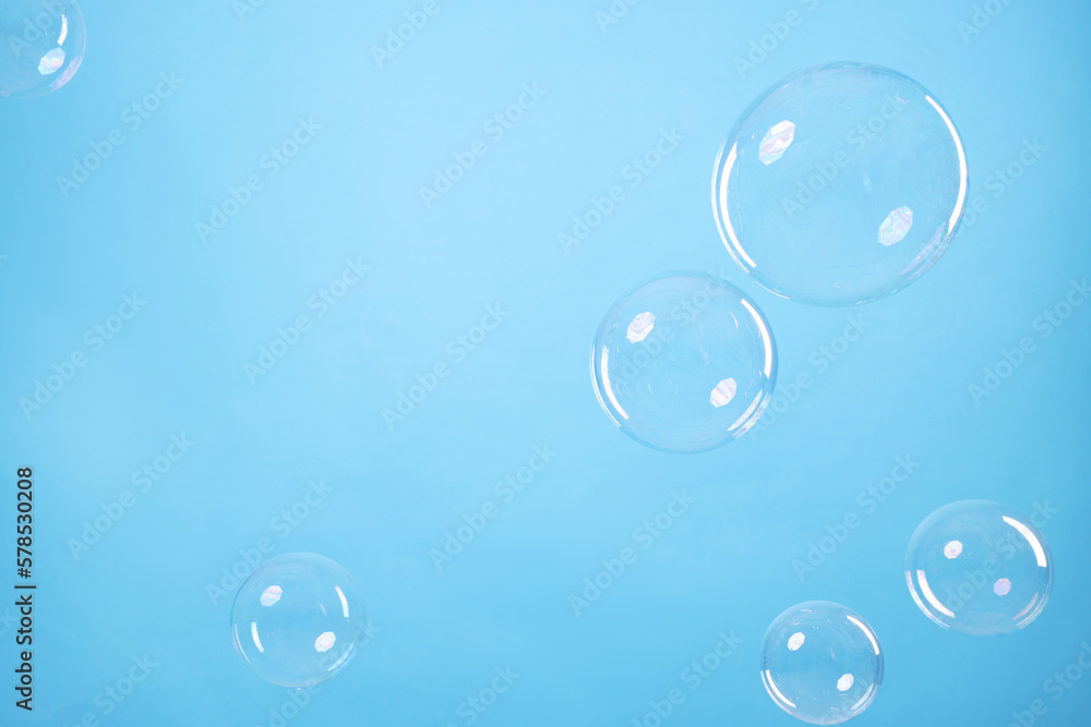 Many beautiful soap bubbles on light blue background. Space for text