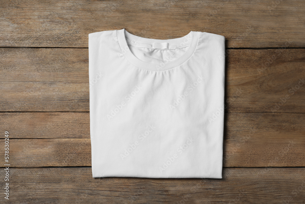 Stylish white T-shirt on wooden table, top view - obrazy, fototapety, plakaty 