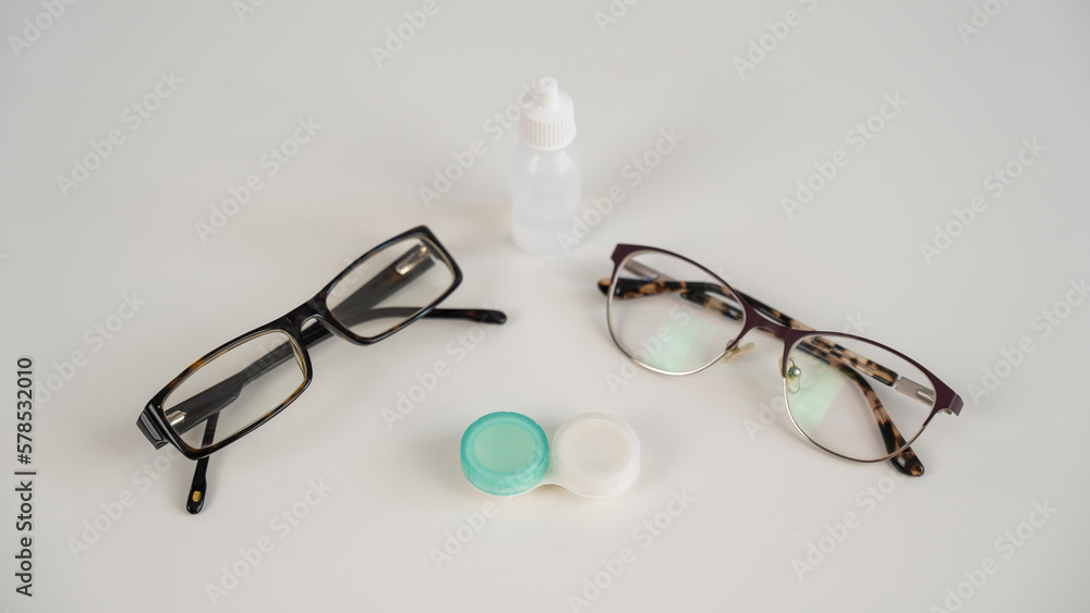 Two pairs of glasses lenses and contact drops in the eyes on a white table. Two pairs of glasses lenses and contact drops in the eyes on a white table.
