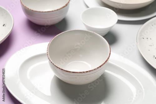Clean ceramic dishes on lilac and grey background