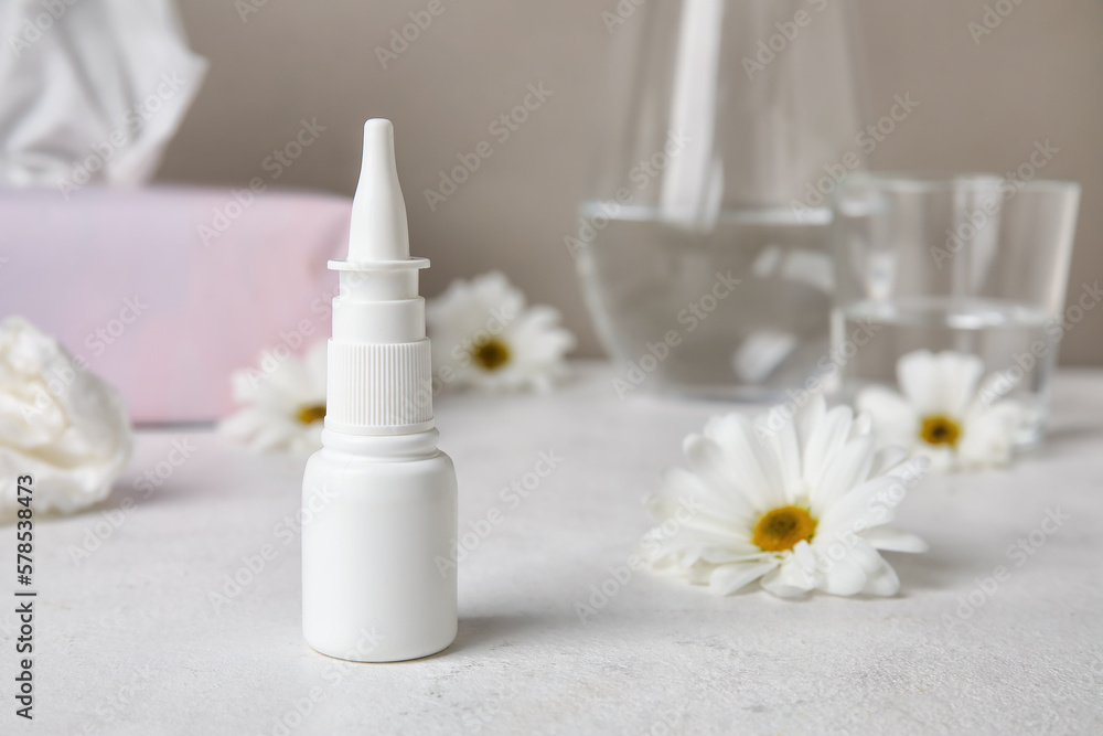 Nasal drops with flowers on white table. Seasonal allergy concept