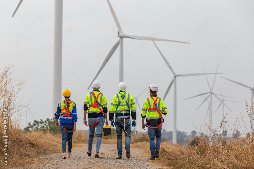 Back view, Teamwork engineer worker wearing safety uniform discuss operational planning at wind turbine field renewable energy. technology protect environment reduce global warming problems. Back view, Teamwork engineer worker wearing safety uniform discuss operational planning at wind turbine field renewable energy. technology protect environment reduce global warming problems.