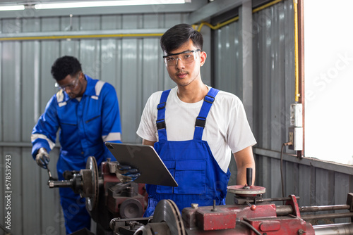 Asian man engineer using digital tablet workers check up usage of brake disc grinder. repair and maintenance service automobile.