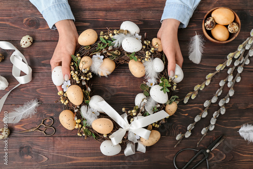 Wall Mural Woman making Easter wreath on dark wooden table, top view