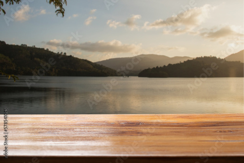 Empty wooden table with lake and sunset background