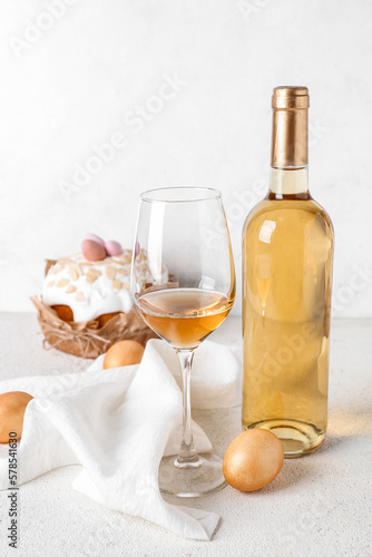 Bottle of wine, glass, Easter eggs and cake on light background