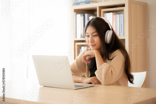Young asian woman wearing headset while working on computer laptop at house. Work at home, Video conference, Video call, Student learning online class © Monster Ztudio