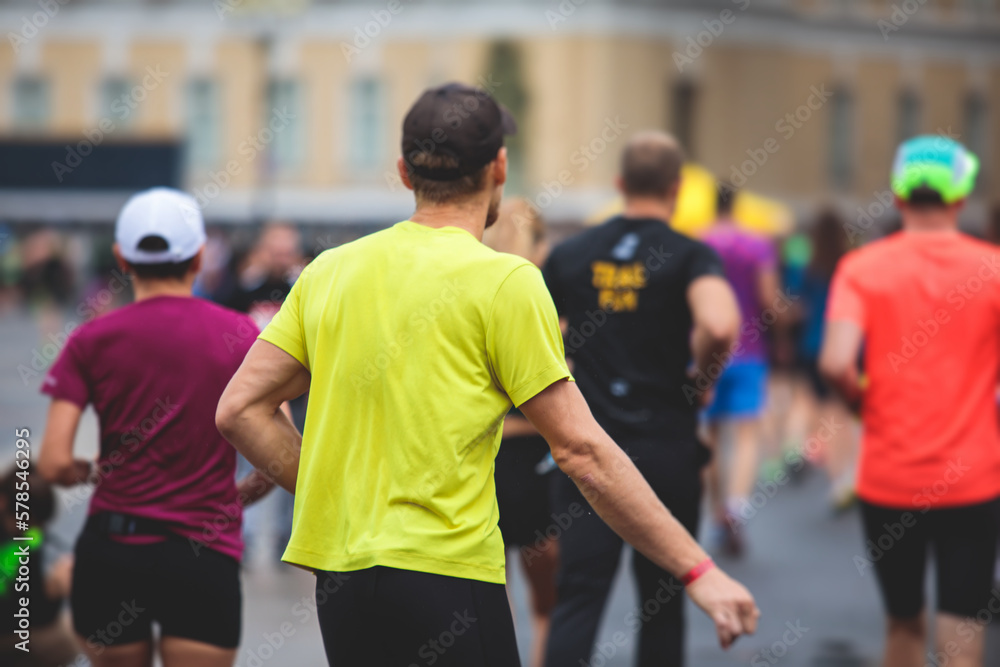 Marathon runners crowd, participants start running the half-marathon in the city streets, crowd of joggers in motion, group athletes outdoor training competition in the rain