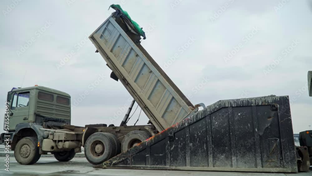 Dump truck unload cargo into special container, side view Dump truck unload cargo into special container, side view