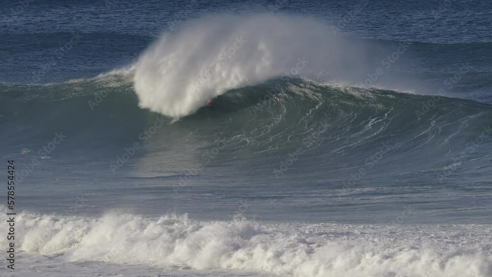 Surfer rides into a barrel created by a huge wave that overwhelms him. Driver in Jetski coming to help Surfer rides into a barrel created by a huge wave that overwhelms him. Driver in Jetski coming to help