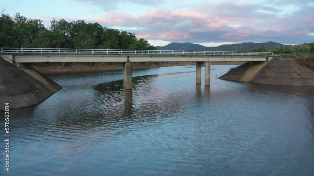 Drone descending and flying underneath a bridge on a lake near to Wivenhoe Dam. Taken at sunset, pink clouds visible. Shot in Brisbane Australia. 4k Drone descending and flying underneath a bridge on a lake near to Wivenhoe Dam. Taken at sunset, pink clouds visible. Shot in Brisbane Australia. 4k