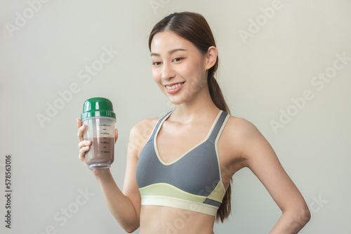 Diet meal replacement for weight loss, smile asian young woman, girl in sportswear, hand in holding protein shake bottle for drink supplement for muscle after workout at home. Healthy body care person © KMPZZZ