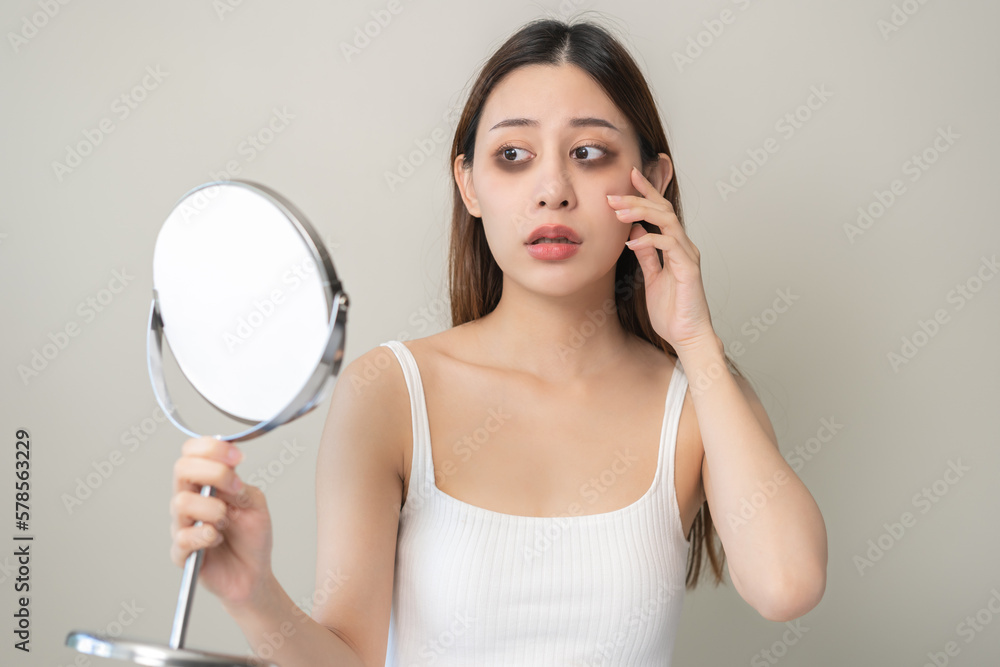Bored, insomnia asian young woman, girl looking at mirror hand touching under eyes with problem of black circles or panda puffy, swollen and wrinkled on face. Sleepless, sleepy healthcare person. Bored, insomnia asian young woman, girl looking at mirror hand touching under eyes with problem of black circles or panda puffy, swollen and wrinkled on face. Sleepless, sleepy healthcare person.
