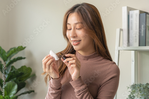 Aromatherapy, cute asian young woman holding cotton pad, bottle of essential perfume oil, enjoying smell fragrance of herbal from medicine natural organic at home. Therapy treatment, beauty skin care.