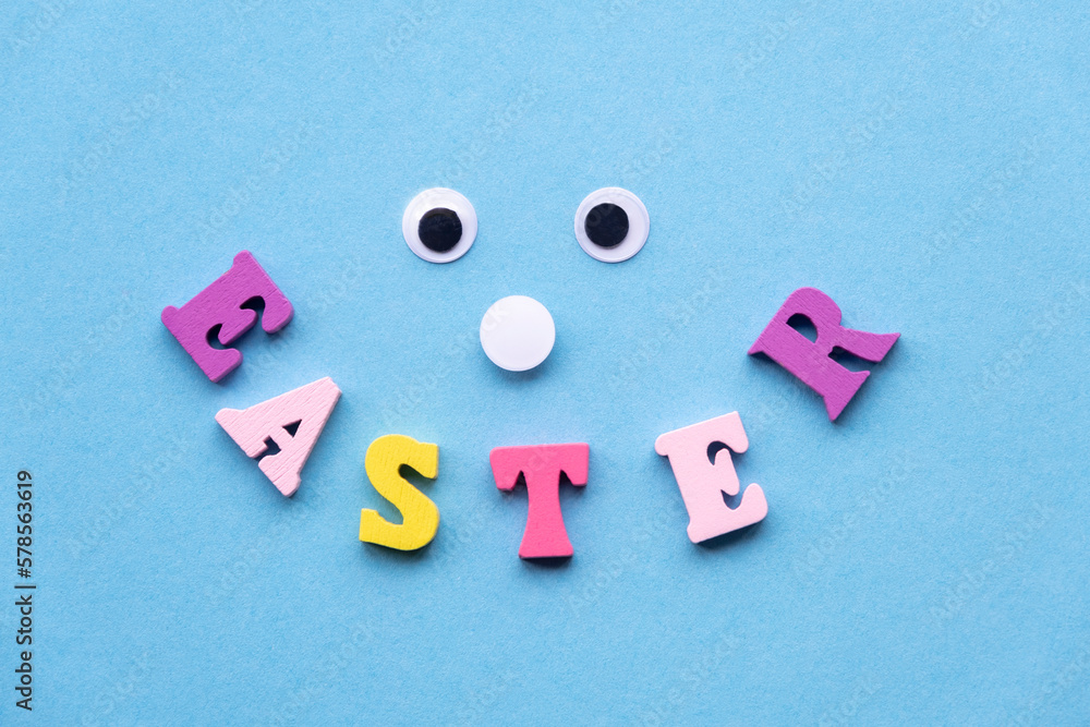 Obraz premium Smile from wooden colored letters on a light blue background. Eyes and smiling mouth, sweet face. Flat lay, copy space