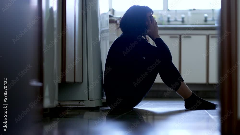 Sad unhappy woman sitting on kitchen floor at home struggling with problems. Depression concept Sad unhappy woman sitting on kitchen floor at home struggling with problems. Depression concept