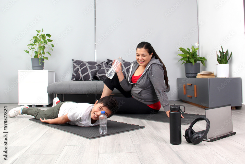 Latino mom and son drink water, hydrate and listen to music after exercising, tired and happy to do their physical activity together, spend quality time together as a family
