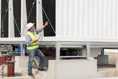 Fotografie Industry engineer under checking the industry cooling tower air conditioner is water cooling tower air chiller HVAC of large industrial building to control air system