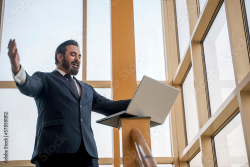 Indian businessman excited and giving winning gesture after looking in laptop