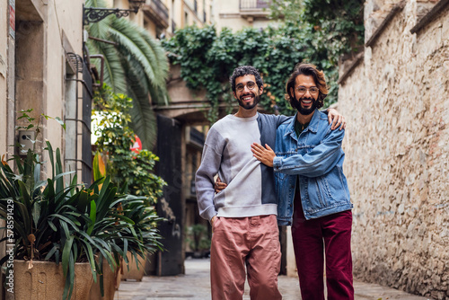 gay couple walking through a beautiful street with plants laughing happy and showing affection, concept of leisure and love between people of the same sex