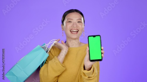 Asian woman, smartphone and green screen mockup in studio with bag, online shopping and deal by backdrop. Gen z model, portrait and phone with mock up space for retail discount by purple background