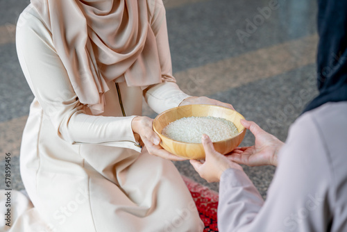 Hands holding a wooden bowl of rice grains for zakat, Islamic zakat concept. Muslims help the poor and needy. Conceptual shoot for property, income, and fitrah zakat.