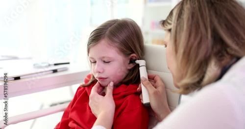 ENT doctor examines child ear with otoscope photo