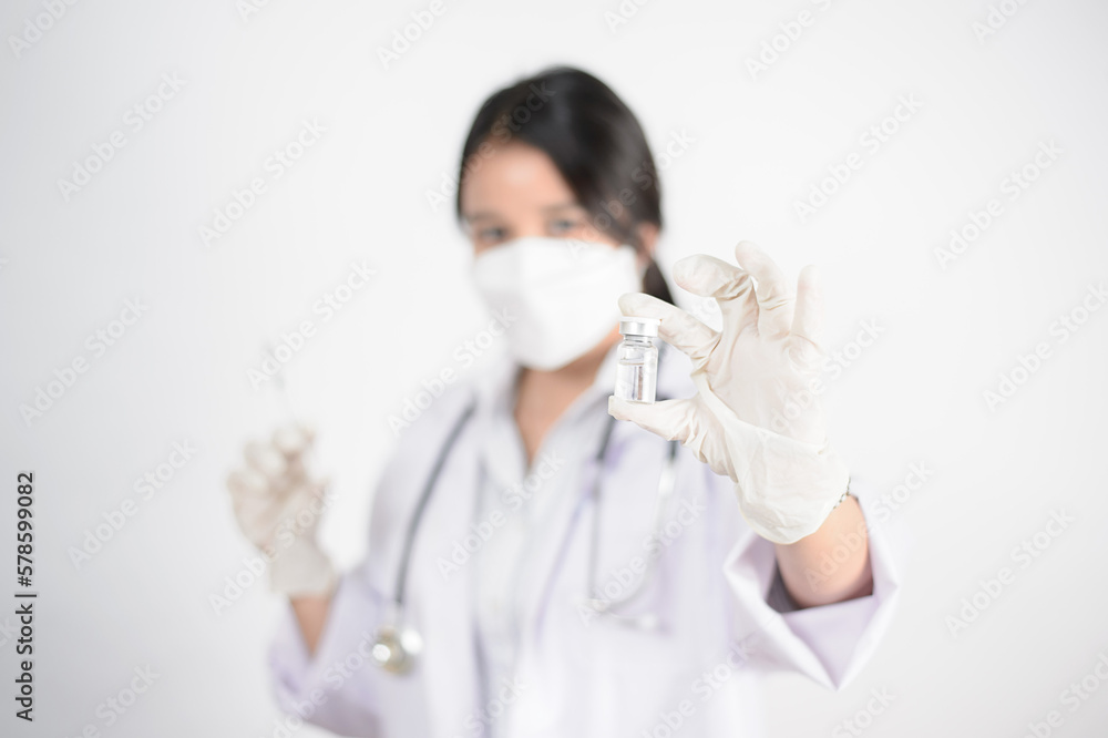 Study of COVID-19 infection. Female doctor examines medicine for illness, man mask with syringe and jar in front with copy space coronavirus virus Study of COVID-19 infection. Female doctor examines medicine for illness, man mask with syringe and jar in front with copy space coronavirus virus
