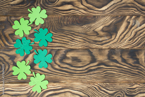 Frame of four-leaf clover and light lights. Wooden background with clover leaves. St. Patrick's Day. Textured wood, blank for holiday greetings. Flat layout. copy space.