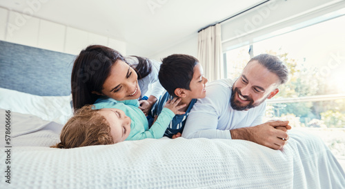 Happy, love and family being playful on the bed together in the bedroom of their modern house. Happiness, excited and children having fun, playing and bonding with their parents in a room at home.
