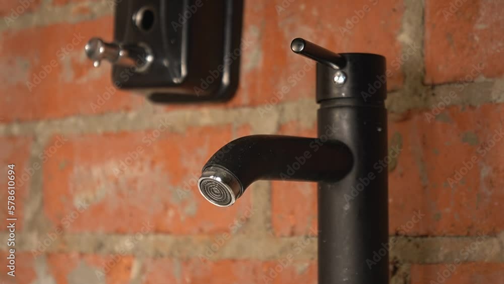 water flows from a black tap against a brick wall. man turned off the tap with water. High quality Full HD video recording water flows from a black tap against a brick wall. man turned off the tap with water. High quality Full HD video recording