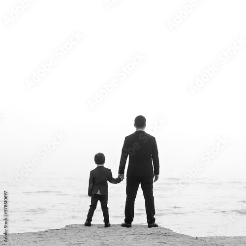 Fotografia Father and son in black suits appear at sea and hold hands
