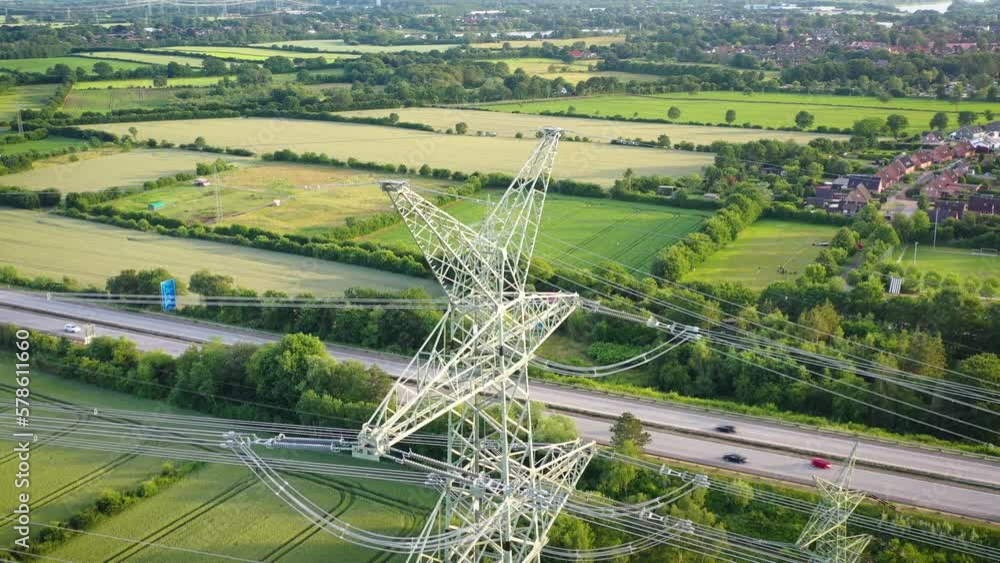 Aerial drone footage of electricity steel pylon tower and highway with moving trucks and cars. Power line near highway. Concept of the infrastructure.