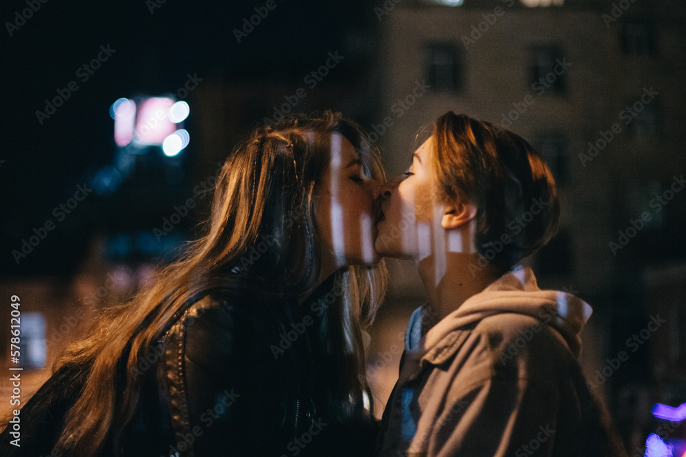 Lesbian couple kissing in city at night Lesbian couple kissing in city at night