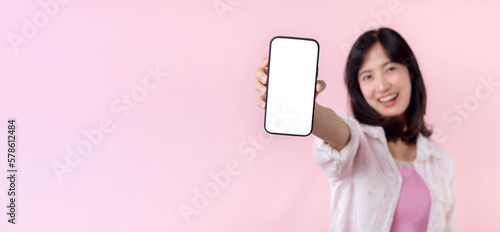 happy smiling young asian woman recommending showing new application or mobile advertisement, mockup smartphone template banner isolated on pink background. Collage blank screen digital mobile device.